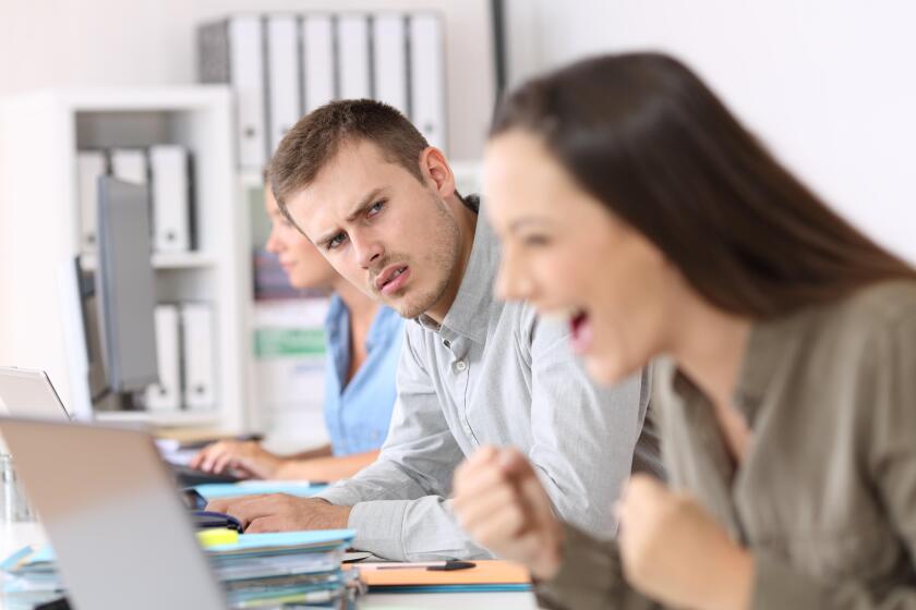 Portrait of a jealous employee looking at a successful colleague at office