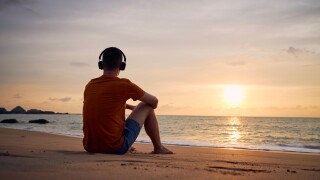 Rear view of man with headphones on beach