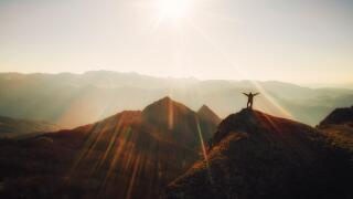 Grateful person standing at the top of the mountain at sunset.Reaching the peak. Business achievement and success concept.Freedom,respect for the natu