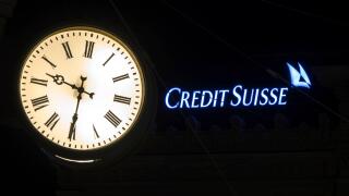 The illuminated logo of Swiss bank Credit Suisse is seen behind a clock at the banks headquarters at Paradeplatz in Zurich, Switzerland on Saturday, March 18, 2023. (Michael Buholzer/Keystone via AP)