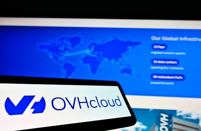 Mobile phone with logo of French cloud computing provider OVH Groupe SAS on screen in front of website. Focus on center-left of phone display.