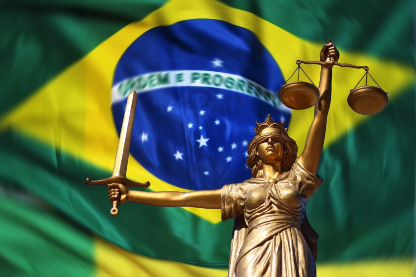 Lady Justice statue against a background of the Brazilian flag