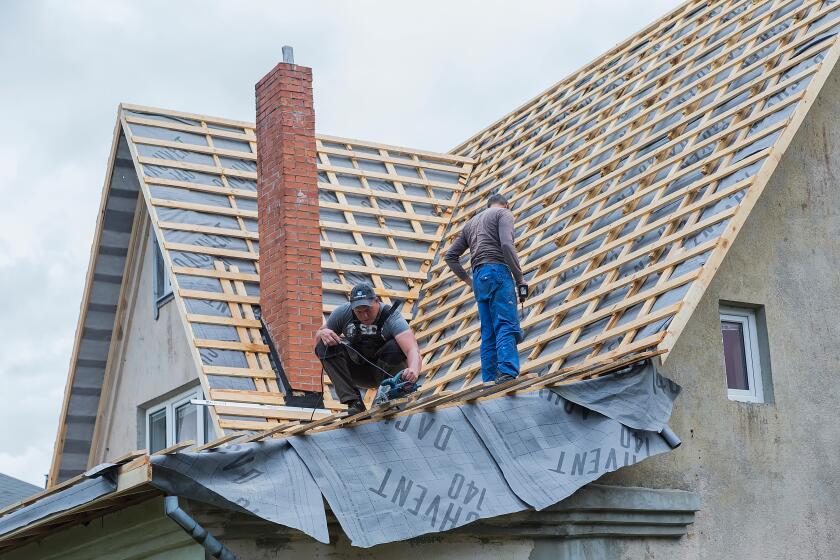 Male carpenters repair the roof of the house.