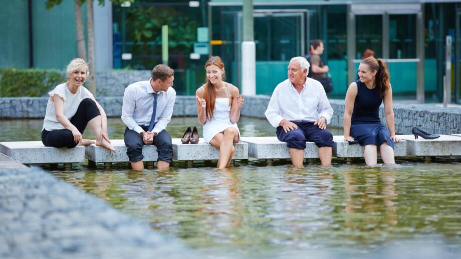 Happy business people talking during break in summer with their feet in water