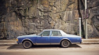 A blue car against a stone wall, Sweden.