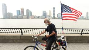 New York, USA - May 28, 2018:  A man with US flag on a bike in Battery Park City Esplanade in New York.