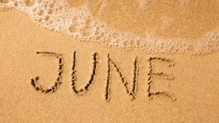 June - written in sand on beach texture, soft wave of the sea