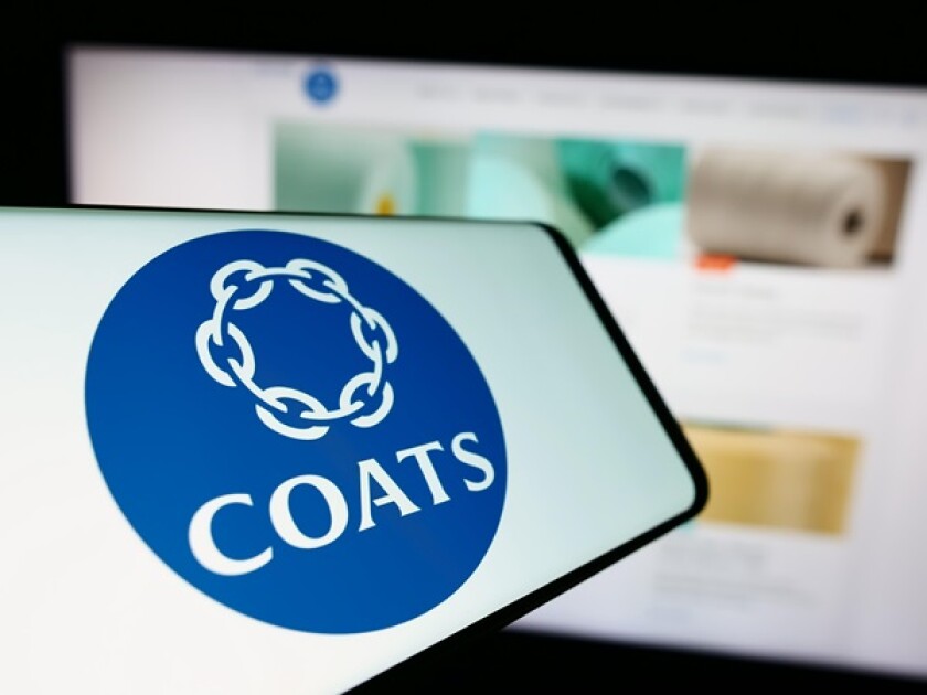 Mobile phone with logo of British textile material company Coats Group plc in front of business website. Focus on center of phone display.