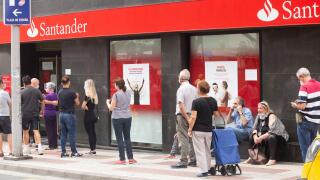 People wearing face masks queuing outside Santander bank during Covid 19, Coronavirus pandemic in Spain