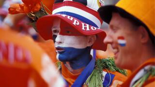 The Netherlands. Amsterdam. Supporters of Dutch football team in national colours. Flag (red, white, blue) and national colour (orange).