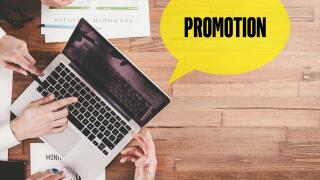 BUSINESS TEAM WORKING IN OFFICE WITH PROMOTION SPEECH BUBBLE ON DESK