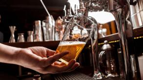 Pour a pint of beer. Bartenders hand holds glass and takes drink from tap