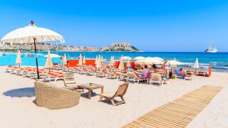 CALVI, CORSICA ISLAND - JUN 28, 2015: A view of Calvi beach with umbrellas and sunbeds on hot summer day, Corsica island, France