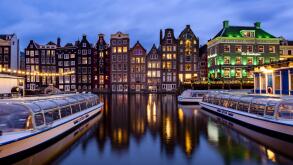 AMSTERDAM, THE NETHERLANDS - JANUARY 18, 2023: Cityscape of traditional Dutch houses during sunset at the Damrak canal in Amsterdam