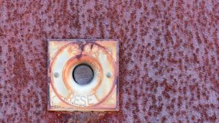 An old stop and reset button mounted on a rusted metal plate