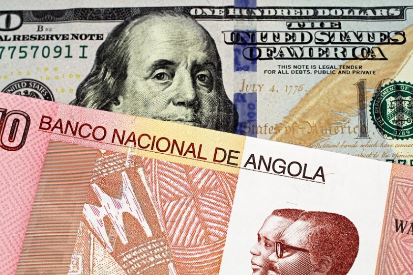 A macro image of a colorful Angolan ten kwanza bill with an American one hundred dollar bill close up