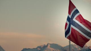 Norwegian flag against snow capped mountains