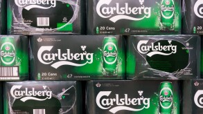 Boxes of Carlsberg beer cans stacked in a supermarket.