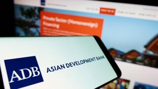 Smartphone with logo of organization Asian Development Bank (ADB) on screen in front of business website. Focus on center-left of phone display.