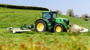 Farmer in a John Deere 6190 with front and rear disc grass cutters cuts the first crop of silage.