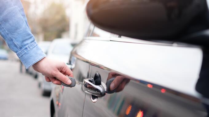 Hand holding a car key and opening the car door lock