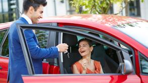 Salesman giving keys to an attractive womans new car
