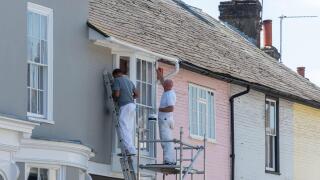Two painters and decorators painting the exterior of a house in the pretty market town of Alresford, Hampshire, England, UK