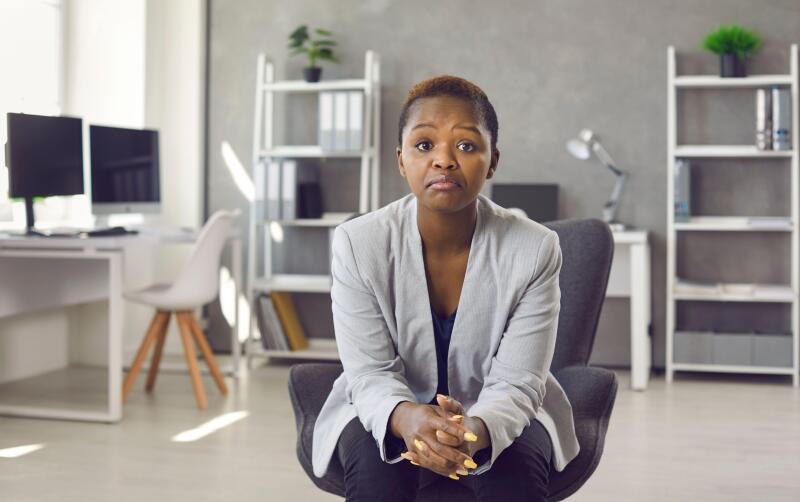 Unimpressed disappointed business woman sitting on office chair and looking at camera