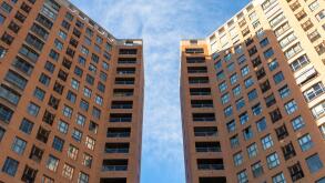 Low angle view of two symmetrical buildings of straight lines with a space between them with a blue sky above them. Architecture concept