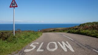 A street to the ocean with a sign and the warning word slow