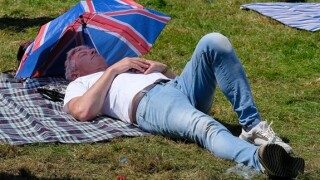 Lulworth, Dorset, UK. 27th July, 2024, man asleep in the shade of a union jack umbrella lying on the grass  at Camp Bestival family festival, 27th July 2024,Credit: Dawn Fletcher-Park/Alamy Live News
