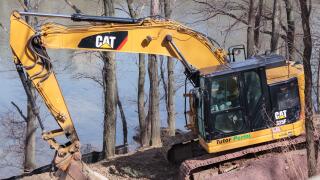 a cat 325f excavator bulldozer parked on the side of a hill on the Hudson River, by Caterpillar brand, with a Tutor Perini label, a major construction
