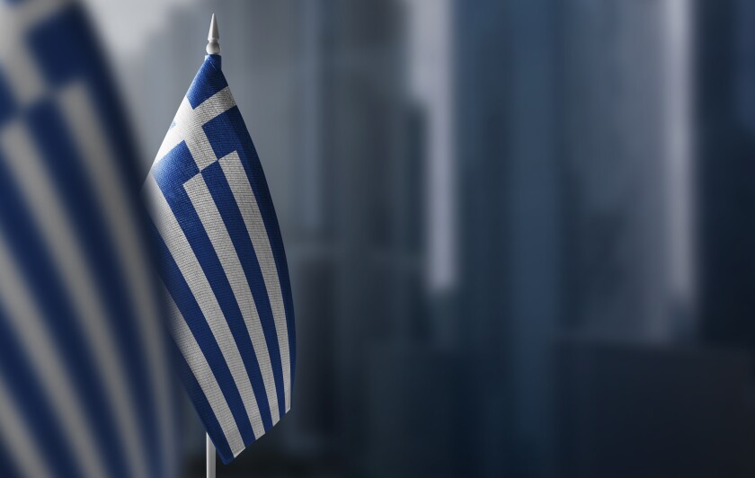 Small flags of Greece on a blurry background of the city