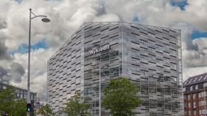 Copenhagen, Denmark - July 24, 2022: Modern gray, glass and steel Nykredit bank building at corner of Puggaardsgade and Kalvebod Brygge under blue clo