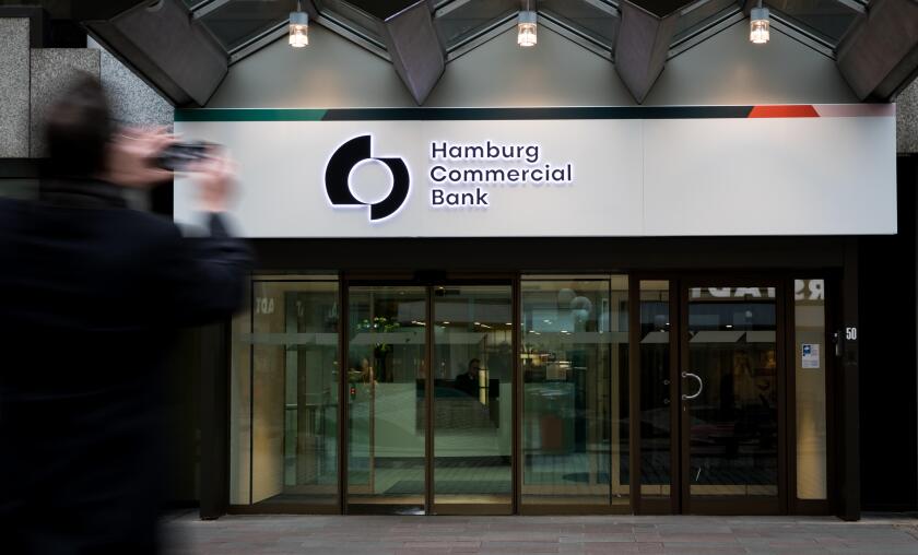 04 February 2019, Hamburg: A man takes a picture with his smartphone of the new logo above the main entrance of the Hamburg Commercial Bank headquarters. (slow shutter recording). Two months after the privatisation, HSH Nordbank now officially bears the n