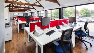 Barn Conversion into office space. Furniture by OEG Interiors. Rows of office desks with computers. Barn rafters.