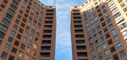 Low angle view of two symmetrical buildings of straight lines with a space between them with a blue sky above them. Architecture concept