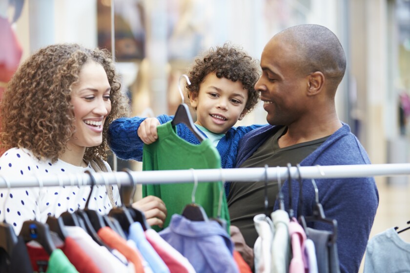 Family Looking At Clothes On Rail In Shopping Mall