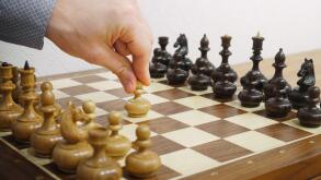 Man's hand making first move in chess game. E2-E4 move. White starts the game.