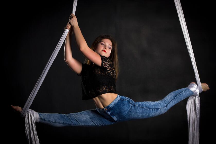 Aerialist woman doing some flexibility and strength tricks on silks