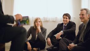 Businesspeople sitting around businessman telling story