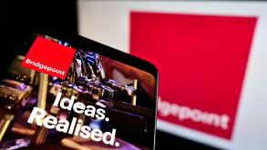 Mobile phone with website of private equity firm Bridgepoint Advisers Ltd on screen in front of business logo. Focus on top-left of phone display.