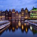 AMSTERDAM, THE NETHERLANDS - JANUARY 18, 2023: Cityscape of traditional Dutch houses during sunset at the Damrak canal in Amsterdam