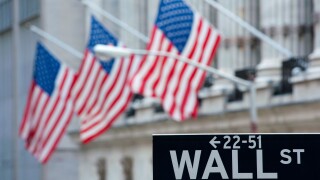 Detail of Wall Street sign with flags on Stock Exchange building to rear Manhattan New York City