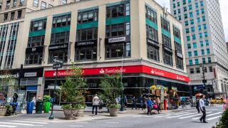 New York City, USA - July 31, 2018: Facade of a bank branch of Santander Bank and a pharmacy with people around in Manhattan, New York City, USA