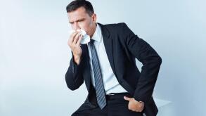 Serious entrepreneur in suit sneezing hard over background