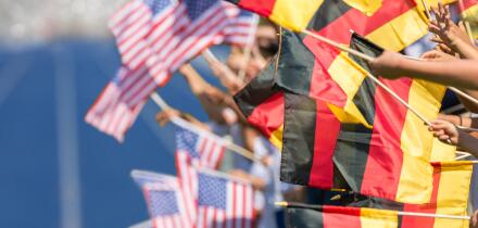 Spectators waving with flags of Germany and USA in front of a blue tartan track. Focus is on the german flags in the foreground