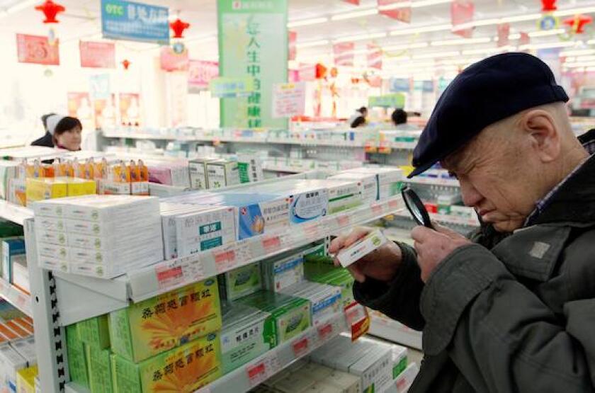 An elderly man uses a magnifiying glass to see the description on a pack of medicine at a pharmacy in Dandong, Liaoning province, China, March 30, 2011.  REUTERS/Jacky Chen/File Photo
