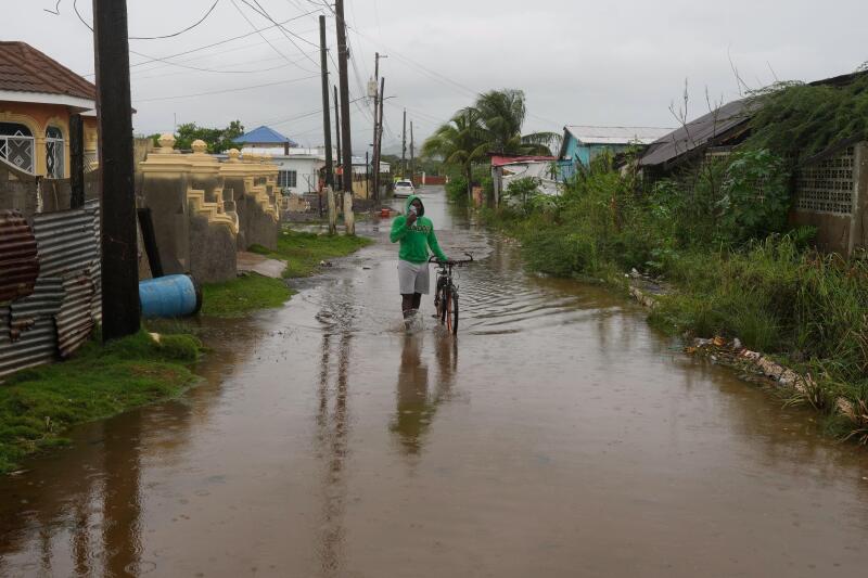 A man wades through a flooded street ahead of the forecasted arrival of Hurricane Melissa in Old Harbour, Jamaica, Monday, Oct. 27, 2025. (AP Photo/Matias Delacroix)