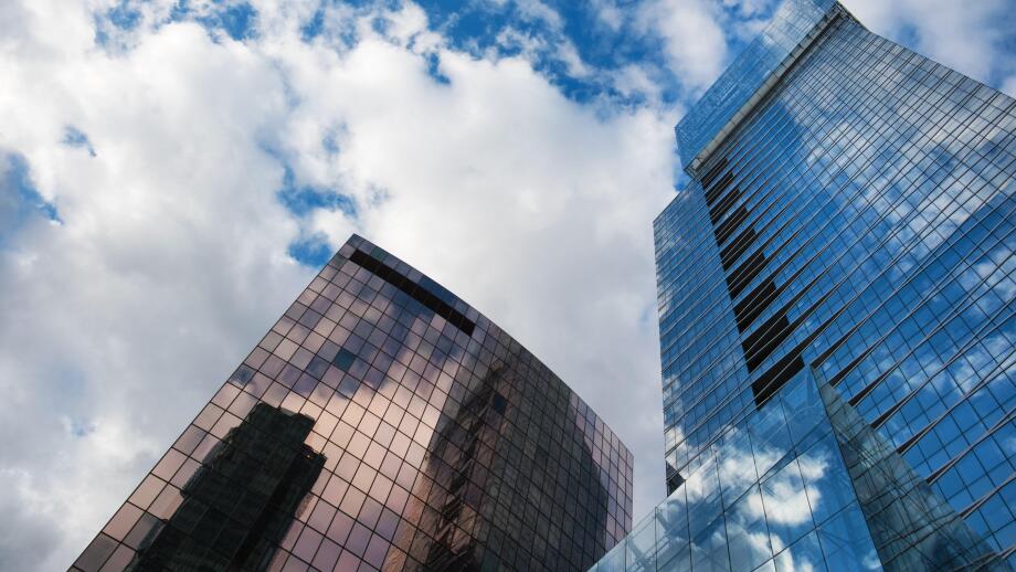 Building architecture with windows reflections and cloudy sky background in La Defense district, Paris, France.